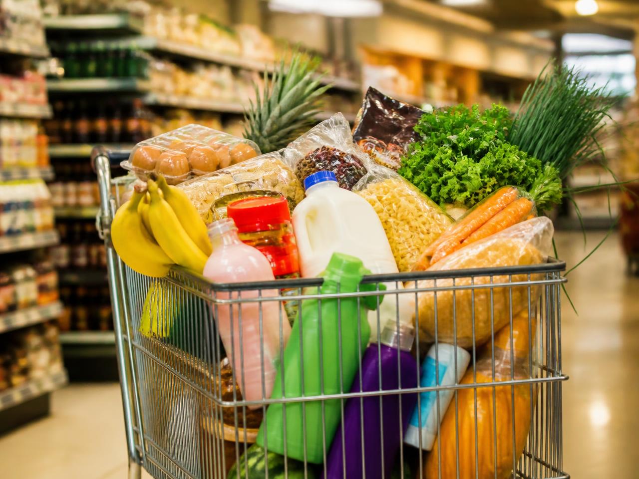 Carrinho de supermercado cheio de produtos de compra recorrente em um corredor de mercado